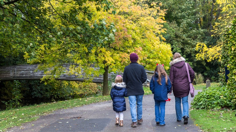 A family walking through the gardens in autumn at Nunnington Hall, Yorkshire